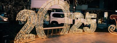 Illuminated 2025 sign on city street with decorative lights creating a festive atmosphere.