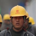 Construction workers in hard hats walking at a site, highlighting teamwork and safety.