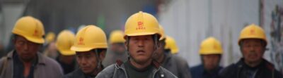 Construction workers in hard hats walking at a site, highlighting teamwork and safety.