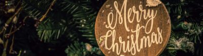 Close-up of a Merry Christmas ornament on a decorated fir tree, evoking festive holiday spirit.